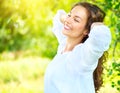 Beautiful young woman enjoying nature outdoor. Happy smiling brunette girl relaxing in the summer park Royalty Free Stock Photo