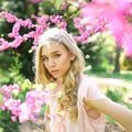 Beautiful young woman enjoying sunny day in park during cherry blossom season on a nice spring day. Royalty Free Stock Photo