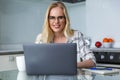 beautiful young woman in eyeglasses smiling at camera while working with laptop