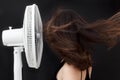 Beautiful young woman face to electric fan enjoying cold wind to refreshing up Royalty Free Stock Photo