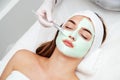 Beautiful young woman with facial mask in beauty salon. Girl getting beauty treatment facial care by beautician Royalty Free Stock Photo