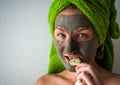 Beautiful young woman with facial mask on her face holding slices of cucumber Royalty Free Stock Photo