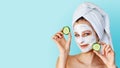 Beautiful young woman with facial mask on her face holding slices of cucumber. Skin care and treatment, spa, natural beauty and Royalty Free Stock Photo