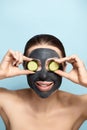 Beautiful young woman with facial mask on her face holding slices of fresh cucumber. Girl beauty Skin care and treatment Royalty Free Stock Photo