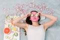 Beautiful young woman with facial mask on her face holding slices of fresh cucumber. Skin care and treatment, spa Royalty Free Stock Photo