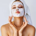 Beautiful young woman with facial mask on her face. Skin care and treatment, spa, natural beauty and cosmetology concept