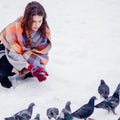 Beautiful young woman feeding birds in winter park Royalty Free Stock Photo