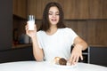 Beautiful young woman feeling hungry eating cupcakes and croissants and drinking milk for breakfast in the kitchen