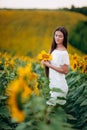 Beautiful young Woman in the field of sunflowers. girl with long brunette hair with sunflower in hand. Summer time Royalty Free Stock Photo