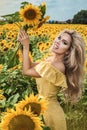 Beautiful young woman in a field of sunflowers in a yellow dress