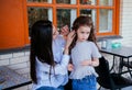 A beautiful young woman fixes her little daughter`s hair. Family leisure and recreation Royalty Free Stock Photo