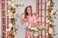 Beautiful young woman with flower in hair keeps bascket full of flowers.