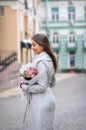 Beautiful young woman with flowers bouquet at city street. Spring portrait of pretty female Royalty Free Stock Photo