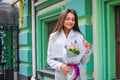 Beautiful young woman with flowers bouquet at city street. Spring portrait of pretty female Royalty Free Stock Photo