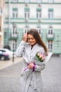 Beautiful young woman with flowers bouquet at city street. Spring portrait of pretty female Royalty Free Stock Photo