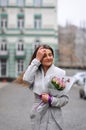 Beautiful young woman with flowers bouquet at city street. Spring portrait of pretty female Royalty Free Stock Photo