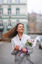 Beautiful young woman with flowers bouquet at city street. Spring portrait of pretty female Royalty Free Stock Photo