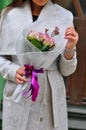 Beautiful young woman with flowers bouquet at city street. Spring portrait of pretty female Royalty Free Stock Photo