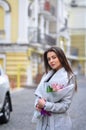 Beautiful young woman with flowers bouquet at city street. Spring portrait of pretty female Royalty Free Stock Photo