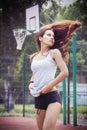 Beautiful young woman with fluttering hair playing basketball outdoors Royalty Free Stock Photo