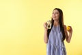 Beautiful young woman with fresh fruit drinking lemon water on yellow background. Space for text Royalty Free Stock Photo