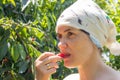 A beautiful young woman in a garden outside the city picks and bites a cherry near a tree on a sunny summer day. Portrait of a Royalty Free Stock Photo