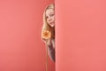 beautiful young woman with gerbera flower peeping behind wall