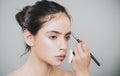 Beautiful young woman getting eyebrow make-up. The artist is applying eyeshadow on her eyebrow with brush. Young model Royalty Free Stock Photo