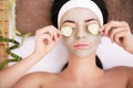 Beautiful young woman is getting facial clay mask at spa, lying Royalty Free Stock Photo