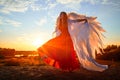 Beautiful young woman or girl in red dress and white wings on the sand on sunny day with blue sky. Angel model or dancer Royalty Free Stock Photo