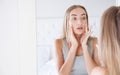 Beautiful young woman,girl is touching her face while looking at the mirror.Trouble on her skin Royalty Free Stock Photo