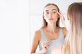 Beautiful young woman,girl is touching her face while looking at the mirror.Trouble on her skin. Royalty Free Stock Photo