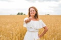 Beautiful young woman giving you thumbs up and smiling in a field with blue sky. Royalty Free Stock Photo