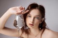 Beautiful young woman with a glass and jewelry in her hands. Professional makeup, expressive eyes