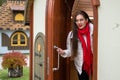 Beautiful young woman in glasses carefully looking around opens an old wooden door and comes out Royalty Free Stock Photo