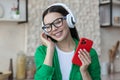 Beautiful young woman in glasses and green shirt relaxing at home in kitchen, listening music Royalty Free Stock Photo