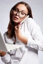 Beautiful young woman in glasses looking at laptop and talking on the phone Royalty Free Stock Photo