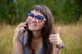 beautiful young woman with glasses talking on the phone and smiling. young adult girl showing thumb up with happy smile Royalty Free Stock Photo
