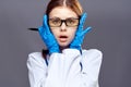 Beautiful young woman in a glove and in medical clothes on a dark gray background holds a pen, doctor, medicine Royalty Free Stock Photo