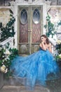 Beautiful young woman in gorgeous blue long dress like Cinderella with perfect make-up and hair style