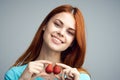 Beautiful young woman on a gray background holds a strawberry, smile, portrait