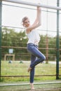 Beautiful young woman on a green football field. Girl standing at football gate, dressed in blue jeans, a white t-shirt