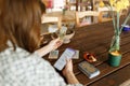 Beautiful young woman is guessing on cards with tarot, runes on wooden table and uses an online app in phone to