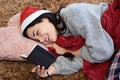 Beautiful young woman happily reading her Christmas wishes wearing a santa claus hat and a sweater Royalty Free Stock Photo