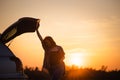 Beautiful young woman happy and dancing in a car`s trunk during a road trip in Europe in the last minutes of Golden Hour Royalty Free Stock Photo