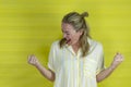 Beautiful young woman happy and excited expressing winning gesture, yellow background