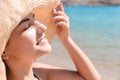 Beautiful young woman in hat is applying sunblock under her eyes and on her nose like Indian. Sun protection concept Royalty Free Stock Photo