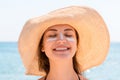 Beautiful young woman in hat is applying sunblock under her eyes and on her nose like Indian. Sun protection concept Royalty Free Stock Photo