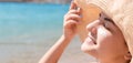 Beautiful young woman in hat is applying sunblock under her eyes and on her nose like Indian. Sun protection concept Royalty Free Stock Photo