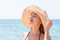 Beautiful young woman in hat is applying sunblock under her eyes and on her nose like Indian. Sun protection concept Royalty Free Stock Photo